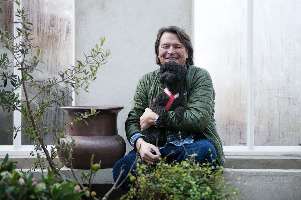 man med liten hund sittandes i ett växthus.