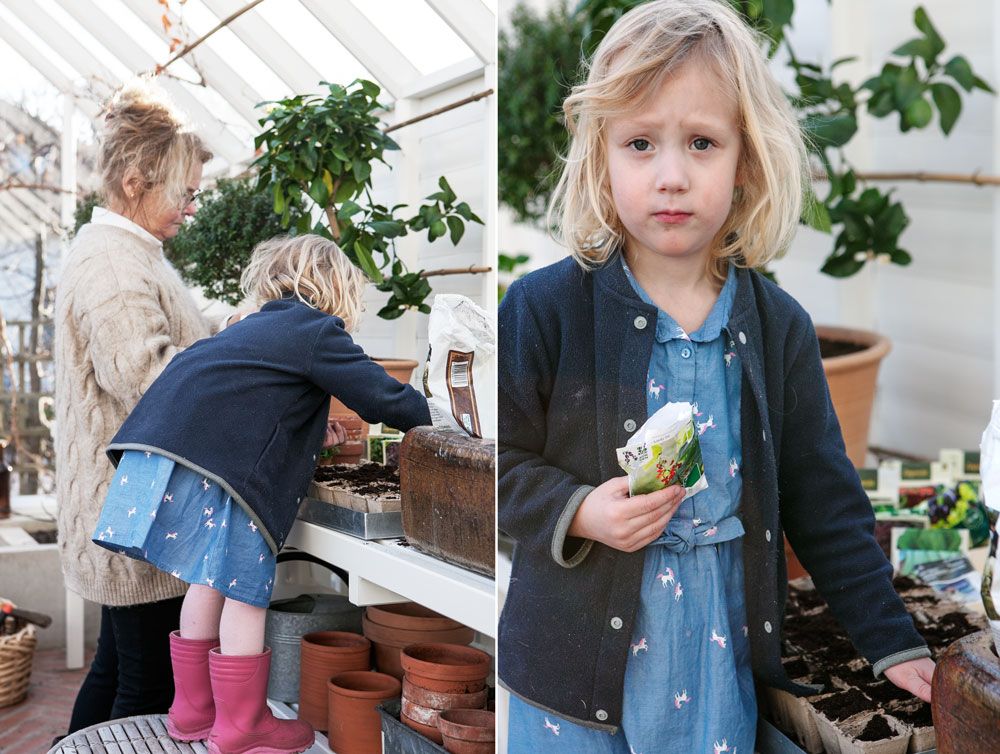 Ett barn och en mamma sår frö vid bänk i växthus.
