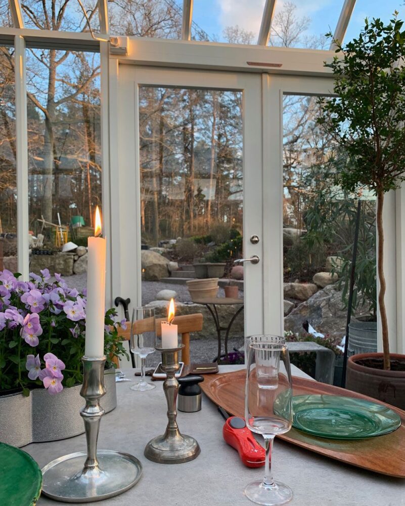 Tända mässingsljusstakar på bord i växthus.