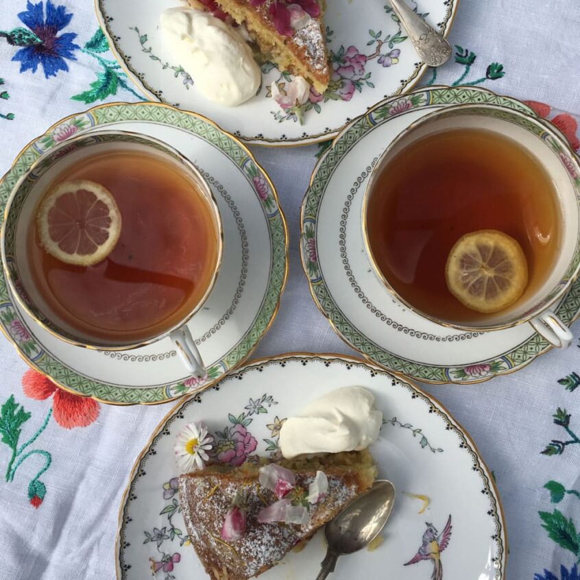 Fyllda tekoppar med citronskiva och kaka på fat.