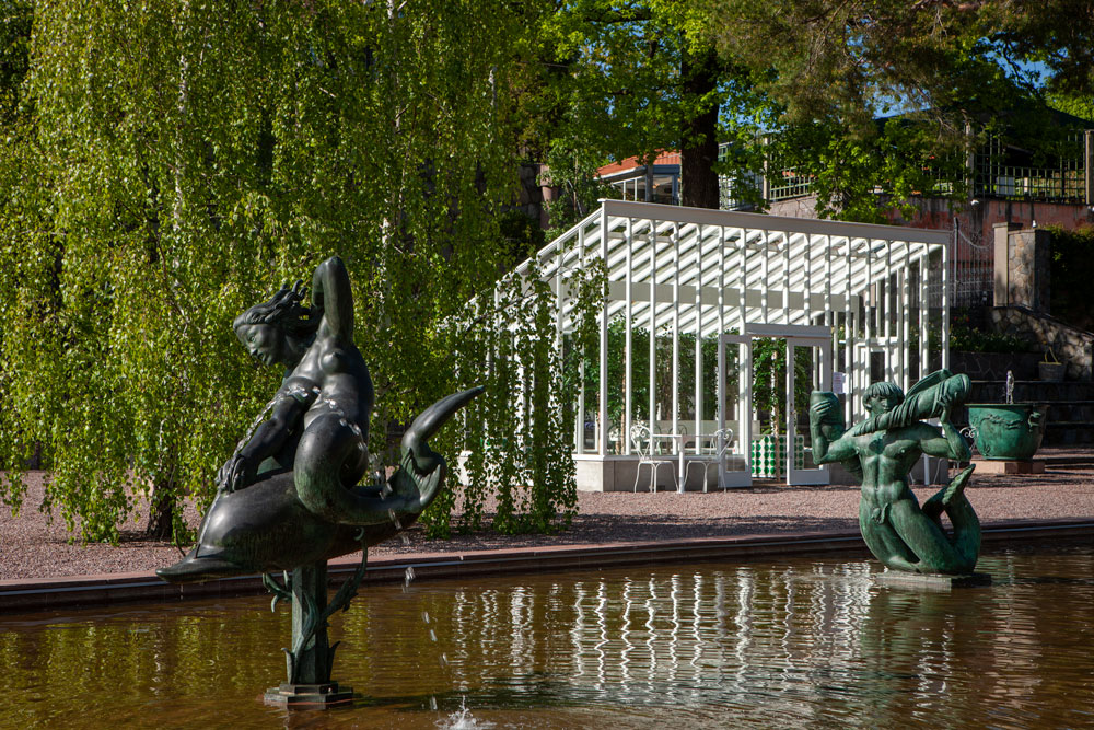 Vitt växthus vid fontän.