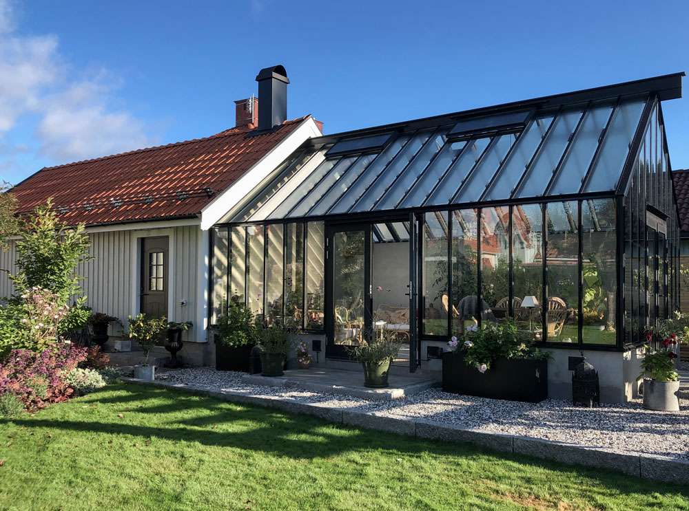 Ett växthus med pulpettak och isolerglas byggt på en terrass.