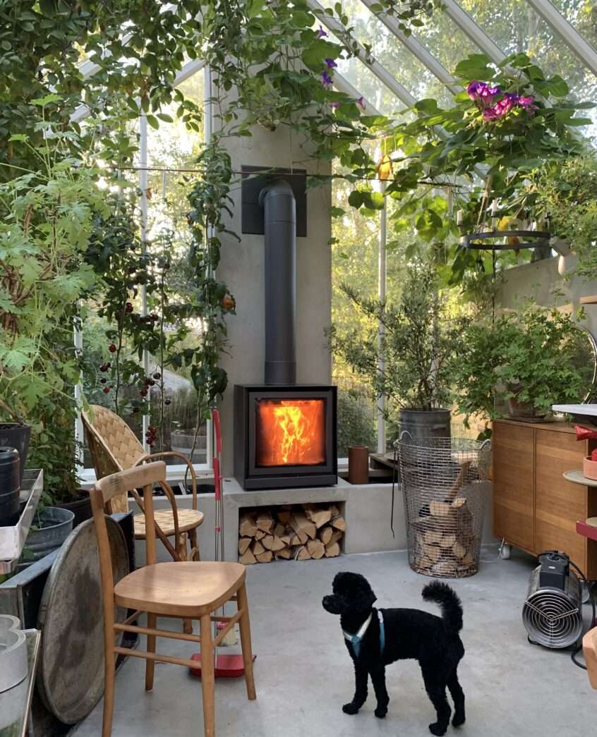 Växthusinteriör med tänd braskamin.
